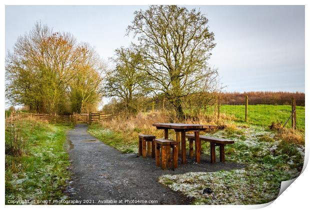 Wooden table and chairs at a seating area on a countryside trail in winter Print by SnapT Photography