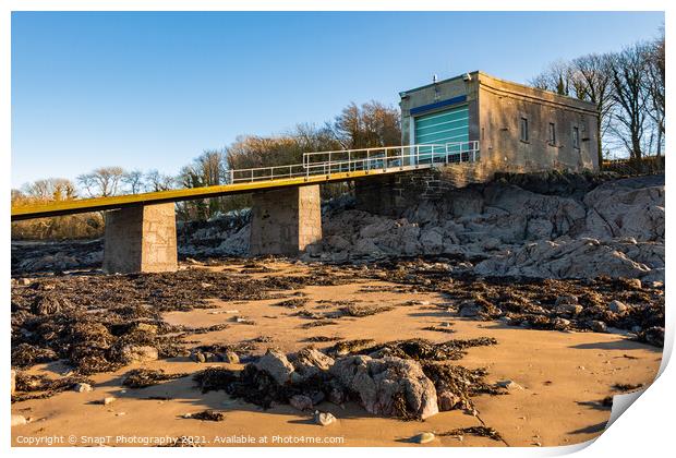 A coastal boat house and boat launch ramp slipway on a rocky beach in winter Print by SnapT Photography