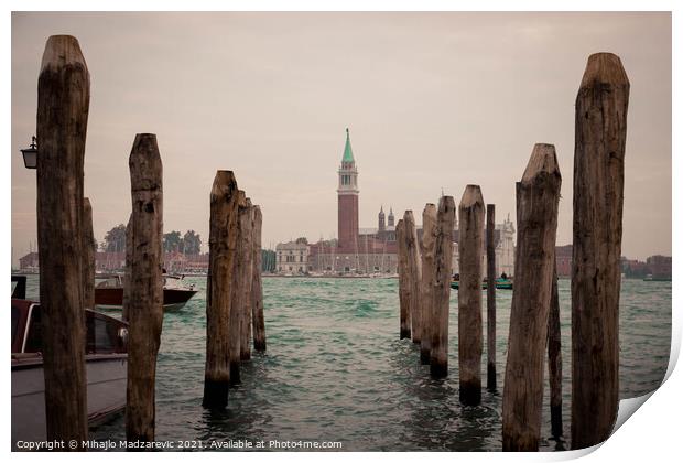 Wooden pillars at Venice bay symmetrically aligned pointing at Italian buildings in the back  Print by Mihajlo Madzarevic