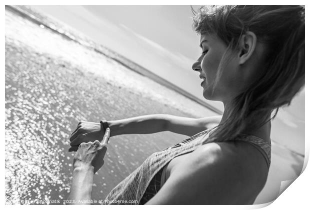 Caucasian female on ocean edge checking sports watch Print by Spotmatik 