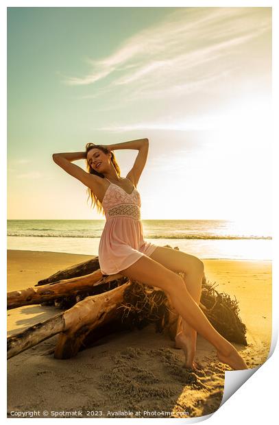 Young Bohemian girl posing on driftwood at sunset Print by Spotmatik 