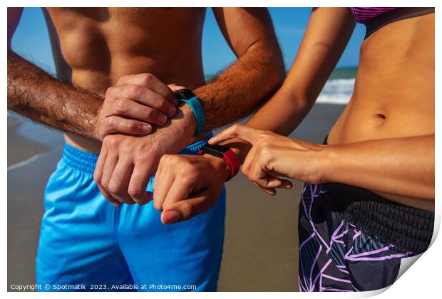 Fit young couple on beach setting activity trackers Print by Spotmatik 