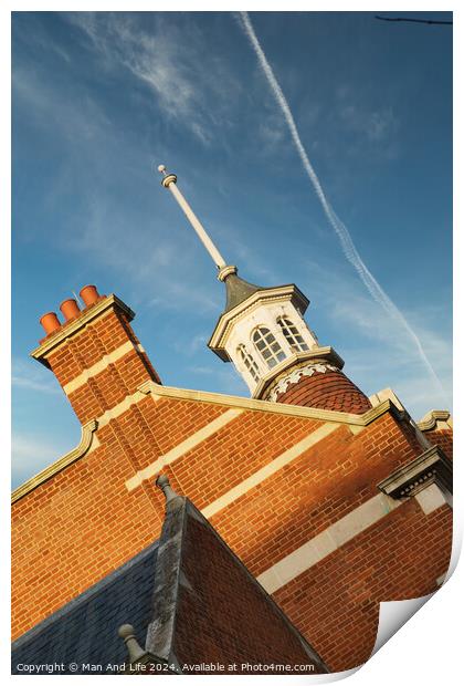 Historic brick building with a distinctive cupola against a blue sky with contrails. Print by Man And Life