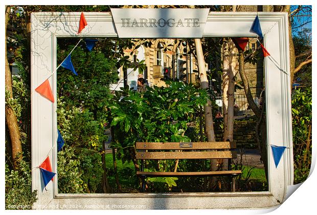 Quaint garden scene framed by a white wooden structure with 'Harrogate' sign, featuring a bench and lush greenery, adorned with colorful pennants. Print by Man And Life