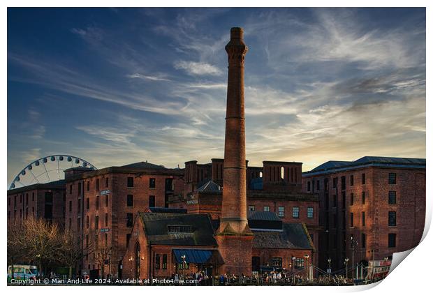 Historic red brick buildings with tall chimney against a dramatic sunset sky, with a Ferris wheel in the background in Liverpool, UK. Print by Man And Life