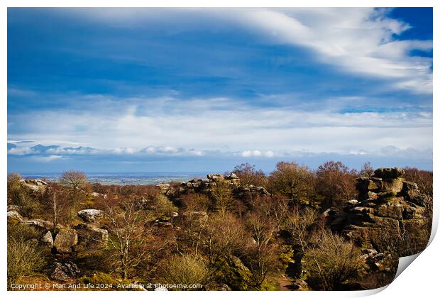 Scenic view of rocky terrain with lush greenery under a blue sky with fluffy clouds, overlooking a distant body of water at Brimham Rocks, in North Yorkshire Print by Man And Life