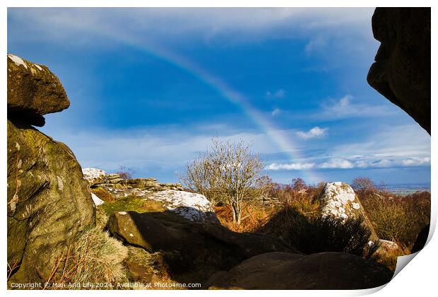 Scenic landscape with a rainbow over a solitary tree, framed by rocky outcrops under a blue sky with clouds at Brimham Rocks, in North Yorkshire Print by Man And Life