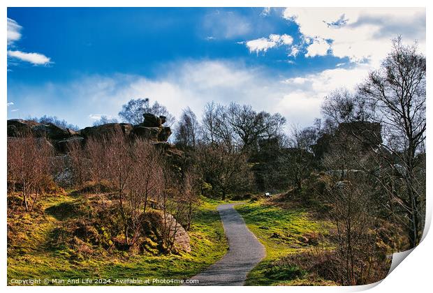 Scenic pathway through a lush park with rocky outcrops and vibrant blue sky with fluffy clouds at Brimham Rocks, in North Yorkshire Print by Man And Life