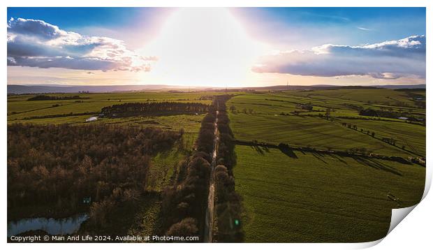 Aerial view of a scenic country road at sunset with lush green fields and a dramatic sky in North Yorkshire. Print by Man And Life