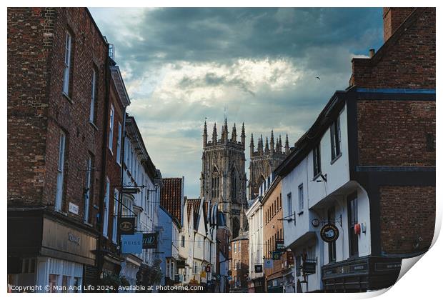 Quaint European street leading to a majestic Gothic cathedral under a dramatic sky at dusk, showcasing historical architecture and urban charm in York, North Yorkshire, England. Print by Man And Life
