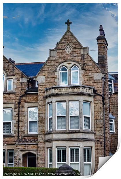 Victorian-style stone building with a gabled roof and bay windows under a blue sky with clouds, showcasing classic architectural details and craftsmanship in Harrogate, North Yorkshire. Print by Man And Life